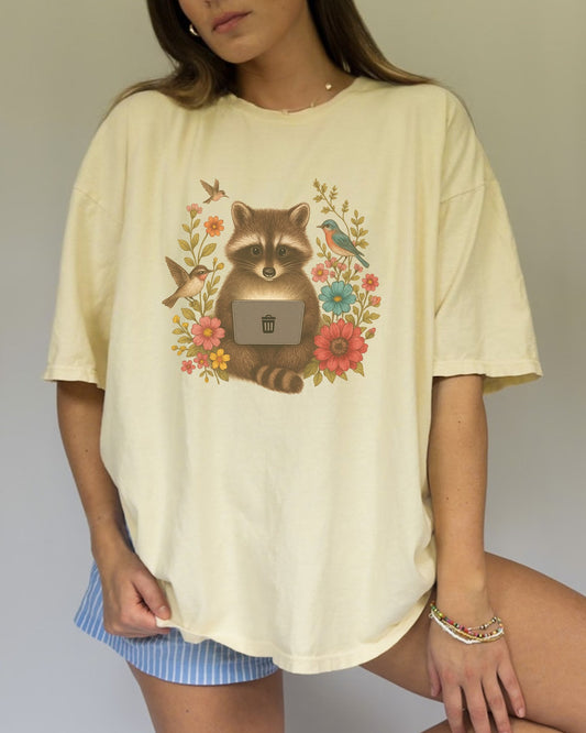 T-shirt with vintage-style raccoon illustration surrounded by colorful wildflowers and birds