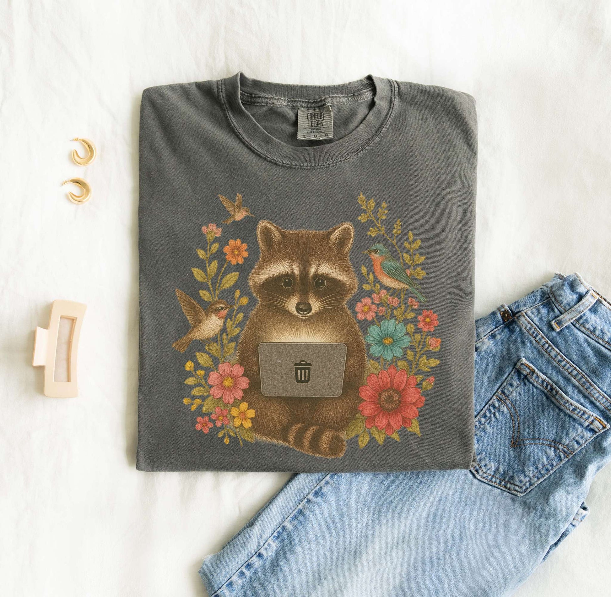 T-shirt with vintage-style raccoon illustration surrounded by colorful wildflowers and birds