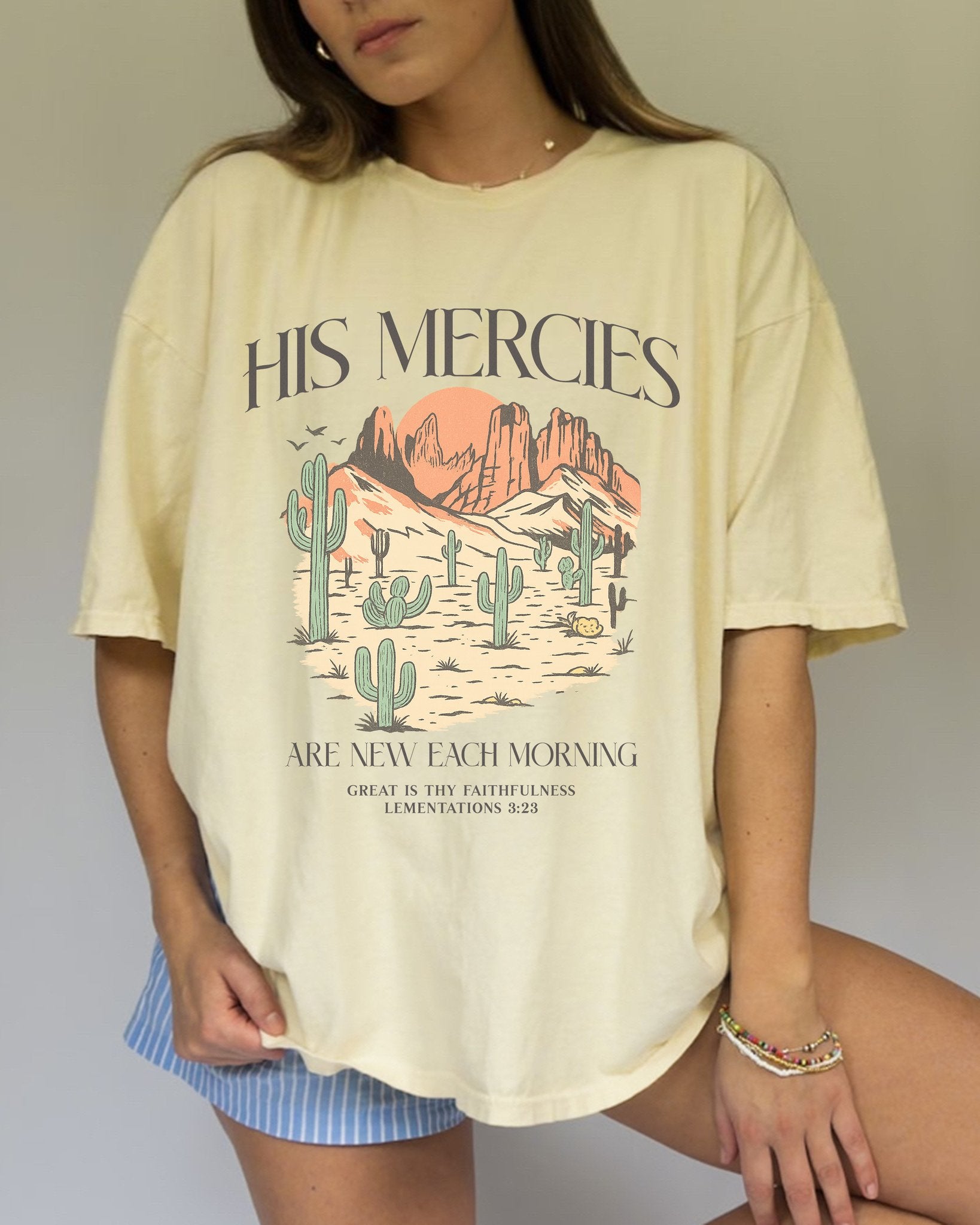 T-shirt with desert landscape design featuring cacti, mountains, and 'His Mercies Are New Each Morning' text with Lamentations 3:23 bible verse