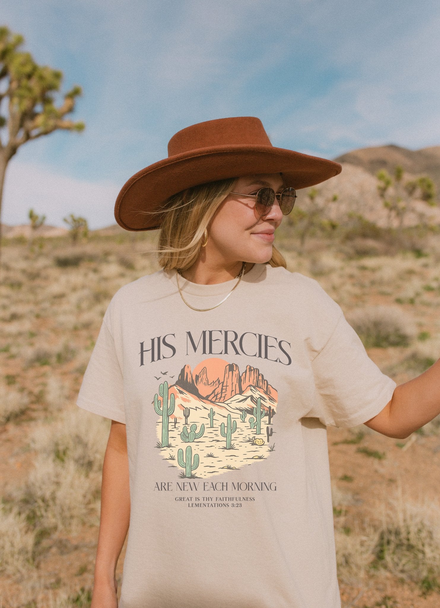 T-shirt with desert landscape design featuring cacti, mountains, and 'His Mercies Are New Each Morning' text with Lamentations 3:23 bible verse