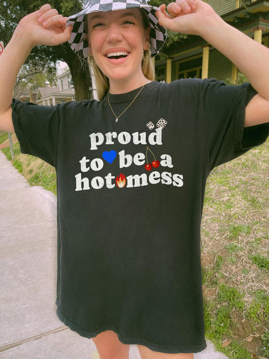 T-shirt with distressed black text reading 'proud to be a hot mess' decorated with dice, blue heart, cherries, and flame graphics