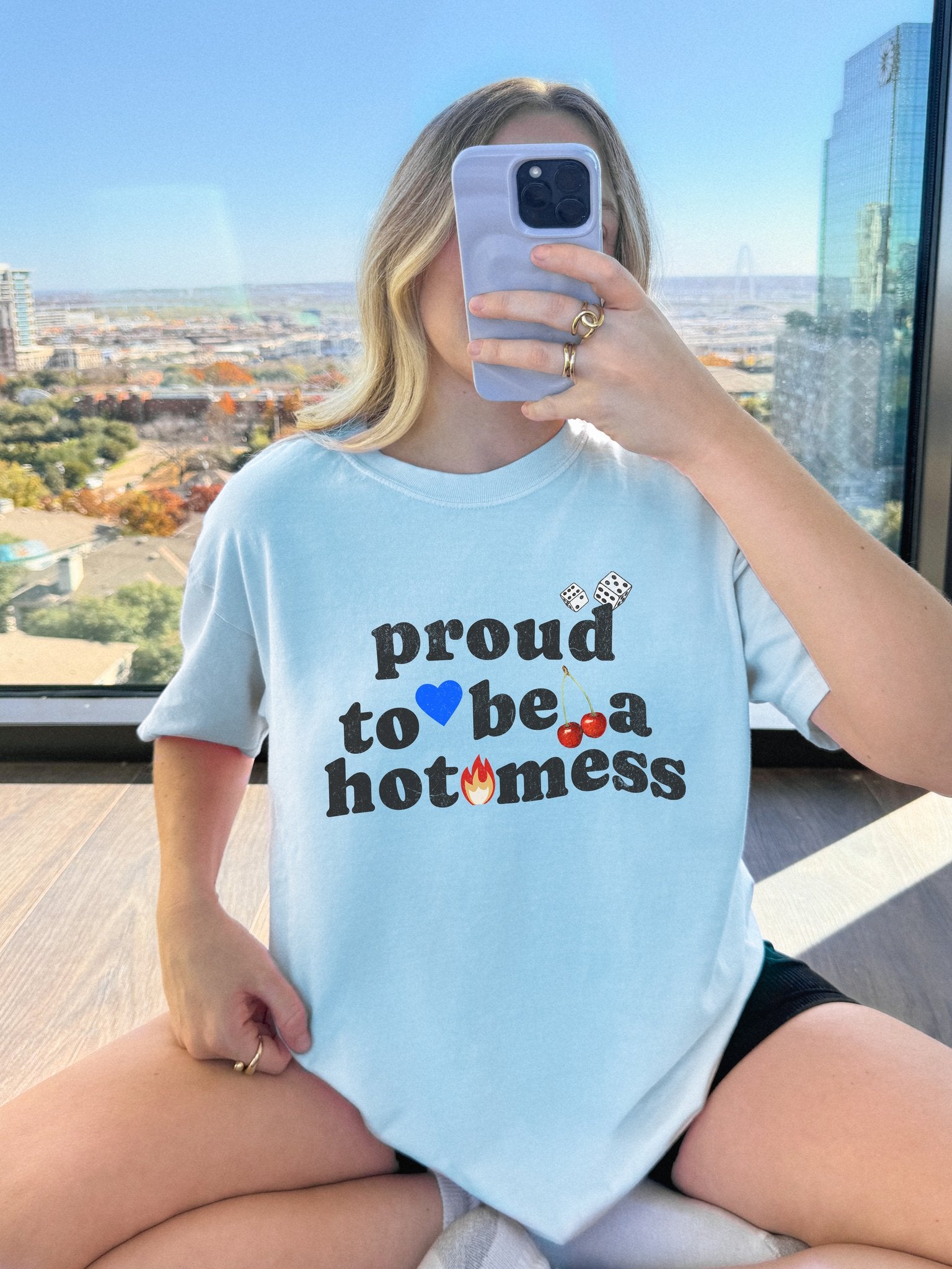 T-shirt with distressed black text reading 'proud to be a hot mess' decorated with dice, blue heart, cherries, and flame graphics
