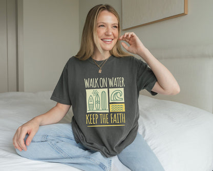 T-shirt with yellow Walk On Water Keep The Faith text, retro surfboard graphics and teal wave designs