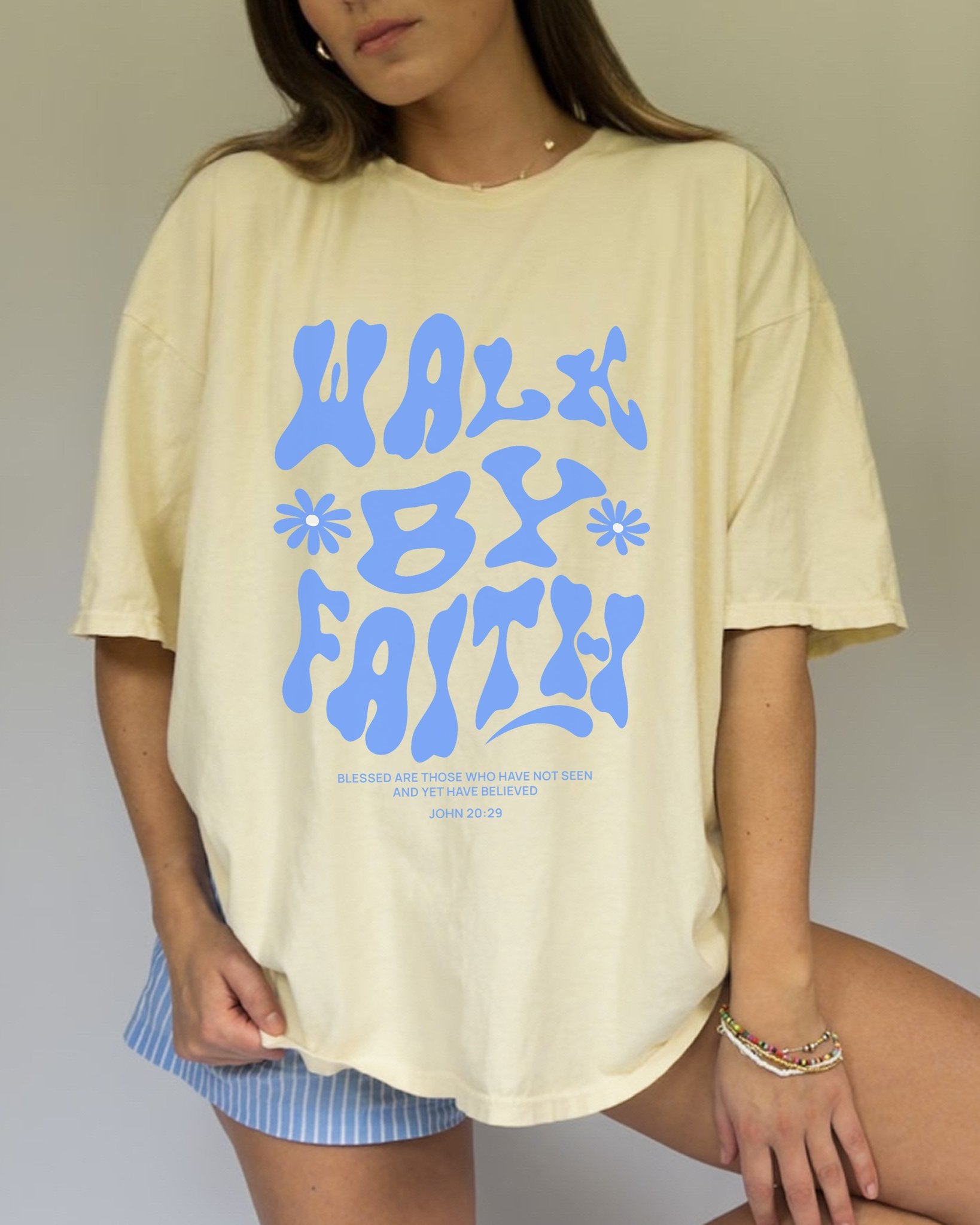 T-shirt with retro wavy font reading 'Walk By Faith' in blue letters with flower accents and John 20:29 scripture