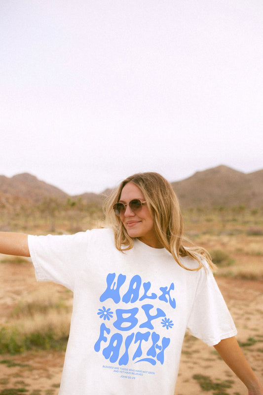 T-shirt with retro wavy font reading 'Walk By Faith' in blue letters with flower accents and John 20:29 scripture