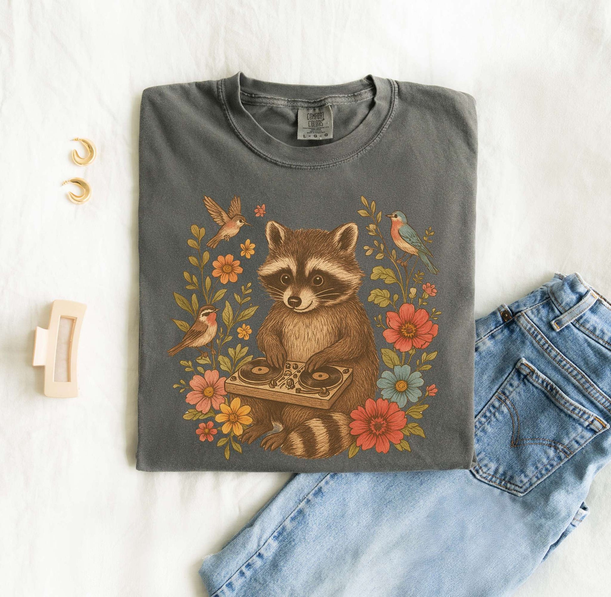 T-shirt with vintage raccoon DJ design surrounded by coral flowers, yellow blooms, and songbirds