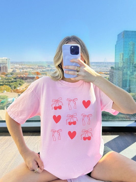 T-shirt with red cherry and bow pattern featuring hearts and ribbon bow designs