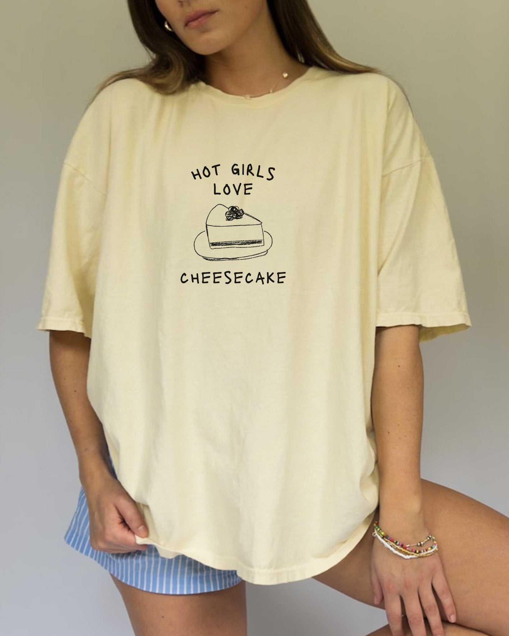 T-shirt with black text reading 'Hot Girls Love' above hand-drawn cheesecake slice illustration