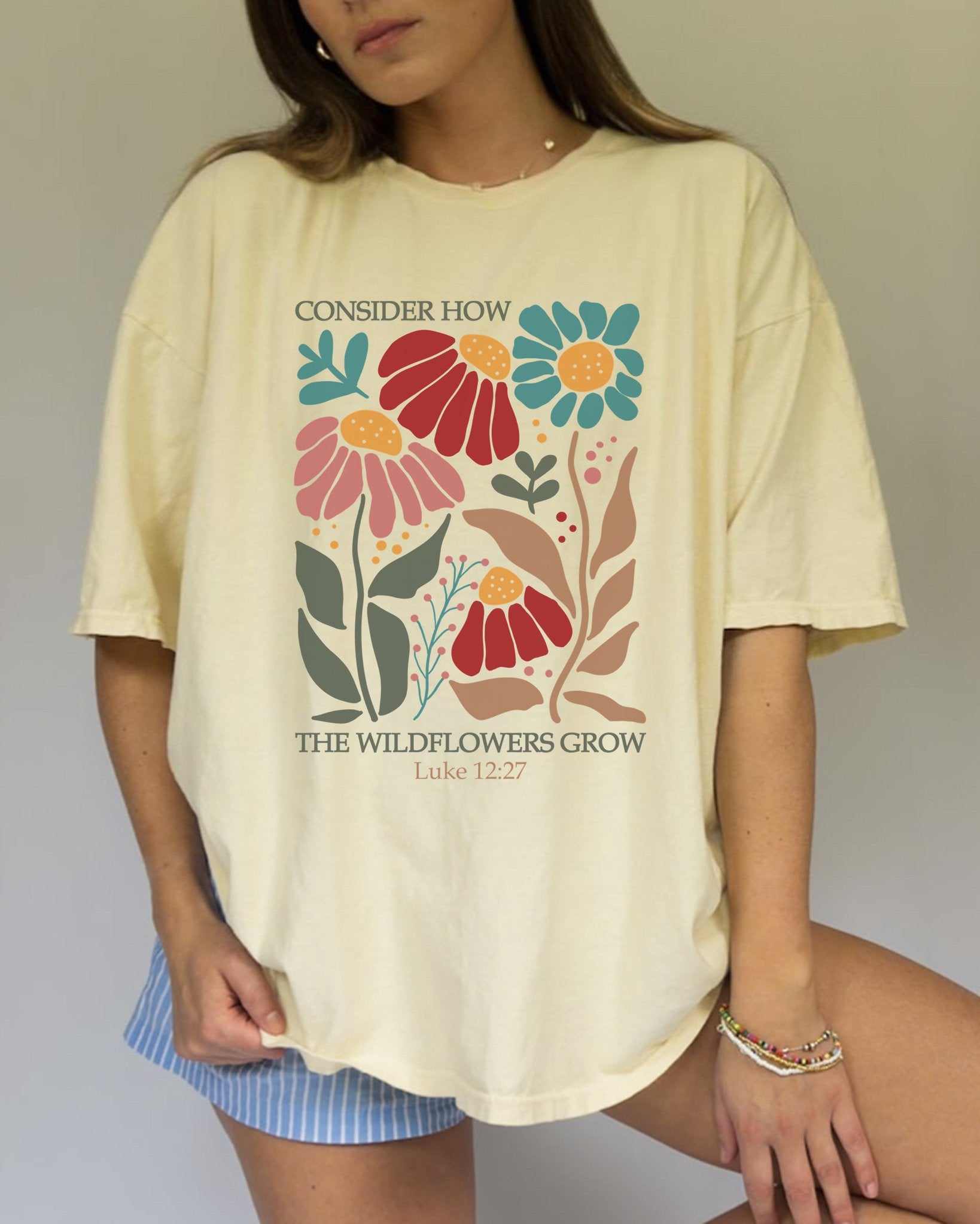 T-shirt with Luke 12:27 Bible verse and colorful wildflowers in red, pink, teal, and brown tones