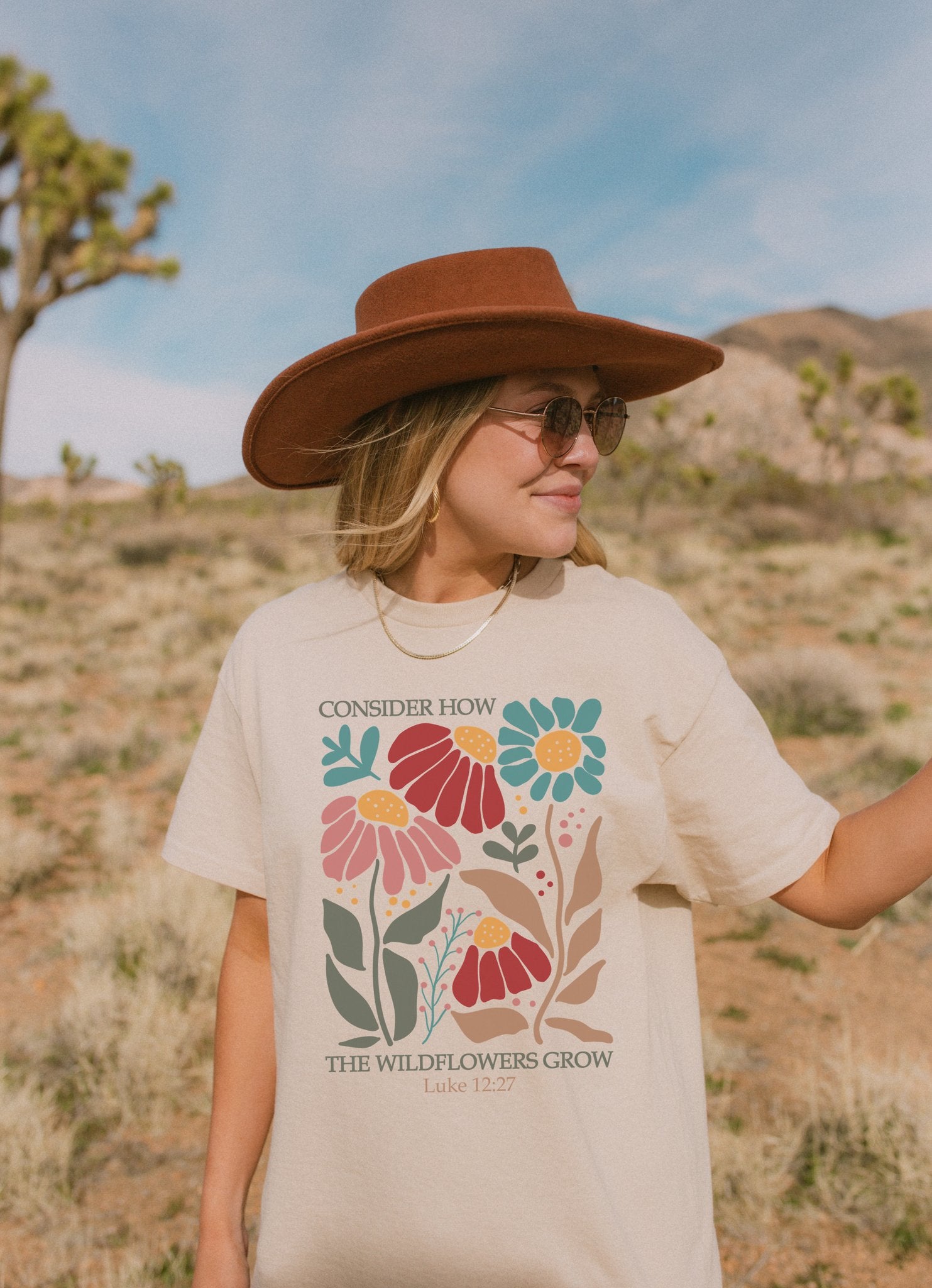 T-shirt with Luke 12:27 Bible verse and colorful wildflowers in red, pink, teal, and brown tones