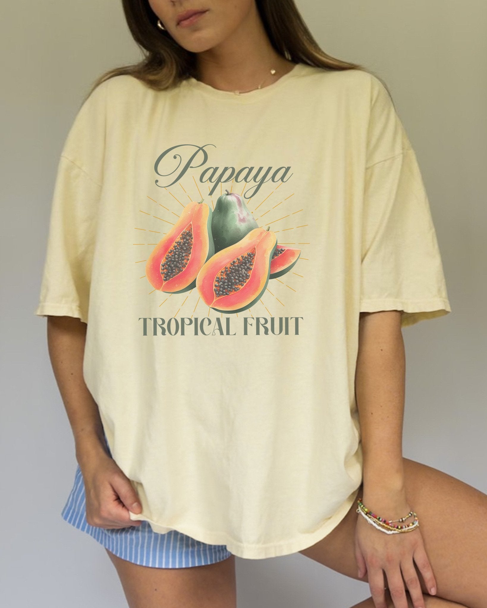 T-shirt featuring watercolor papaya fruits with golden sunburst rays and elegant Papaya script text