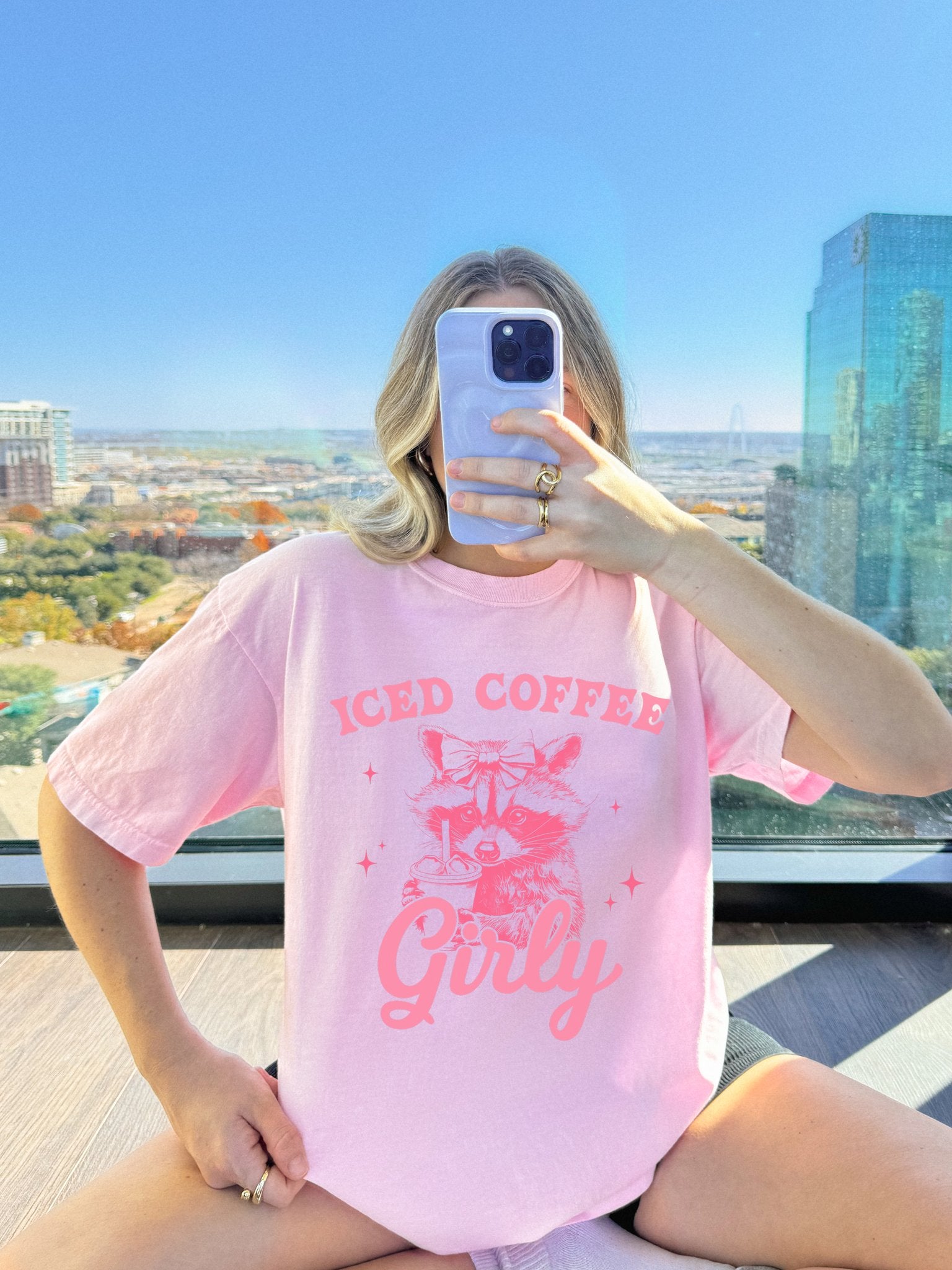T-shirt with pink raccoon wearing bow holding iced coffee cup with 'Iced Coffee Girl' text and stars