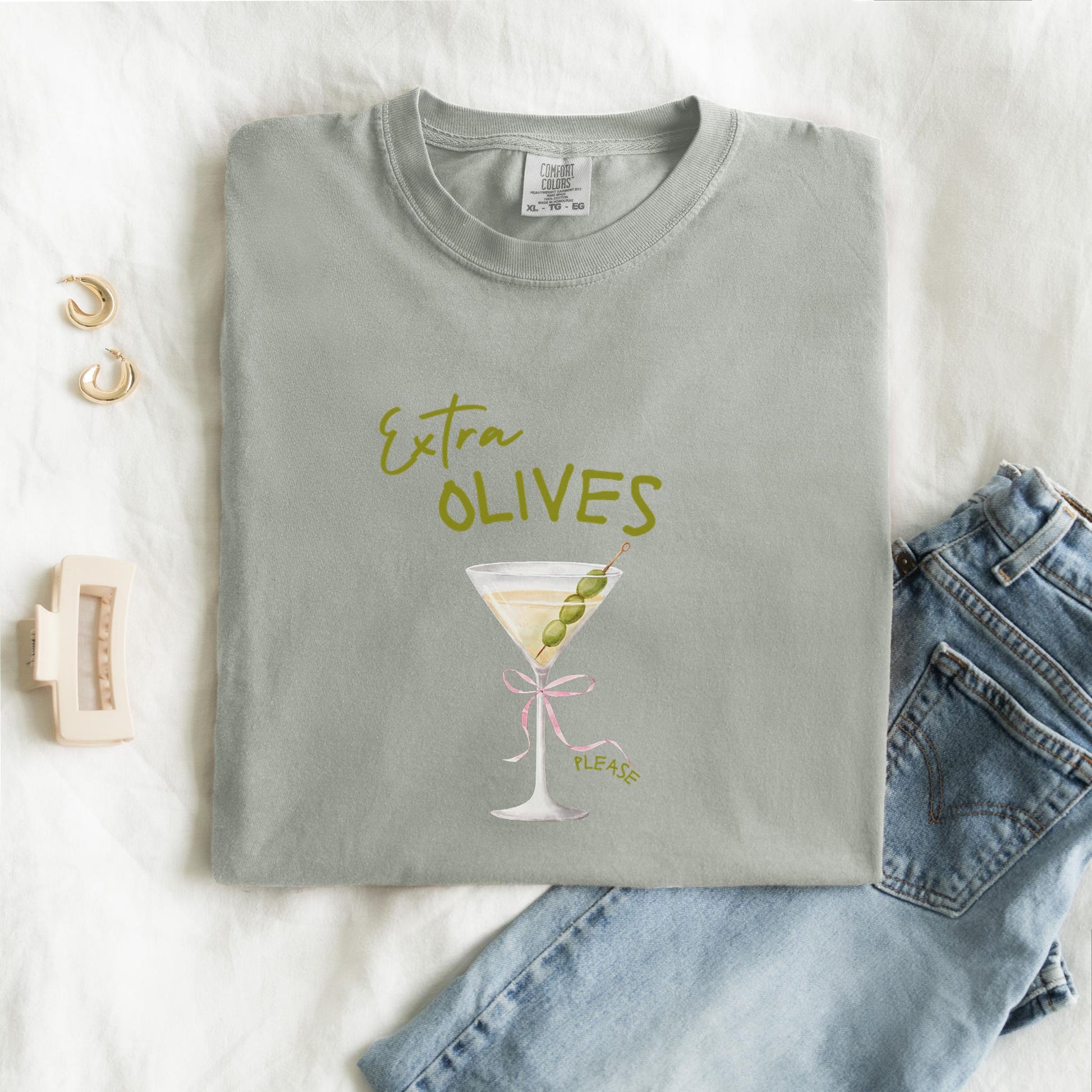 T-shirt design with martini glass, green olives, and pink bow saying Extra Olives Please