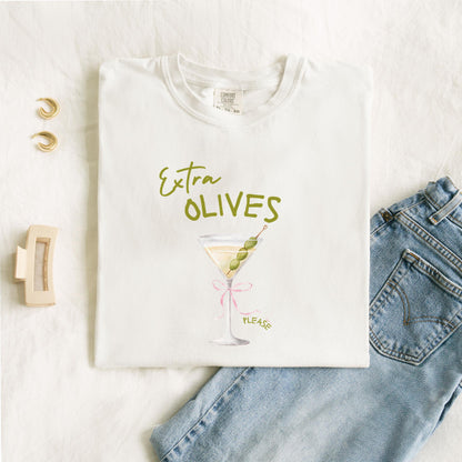 T-shirt design with martini glass, green olives, and pink bow saying Extra Olives Please
