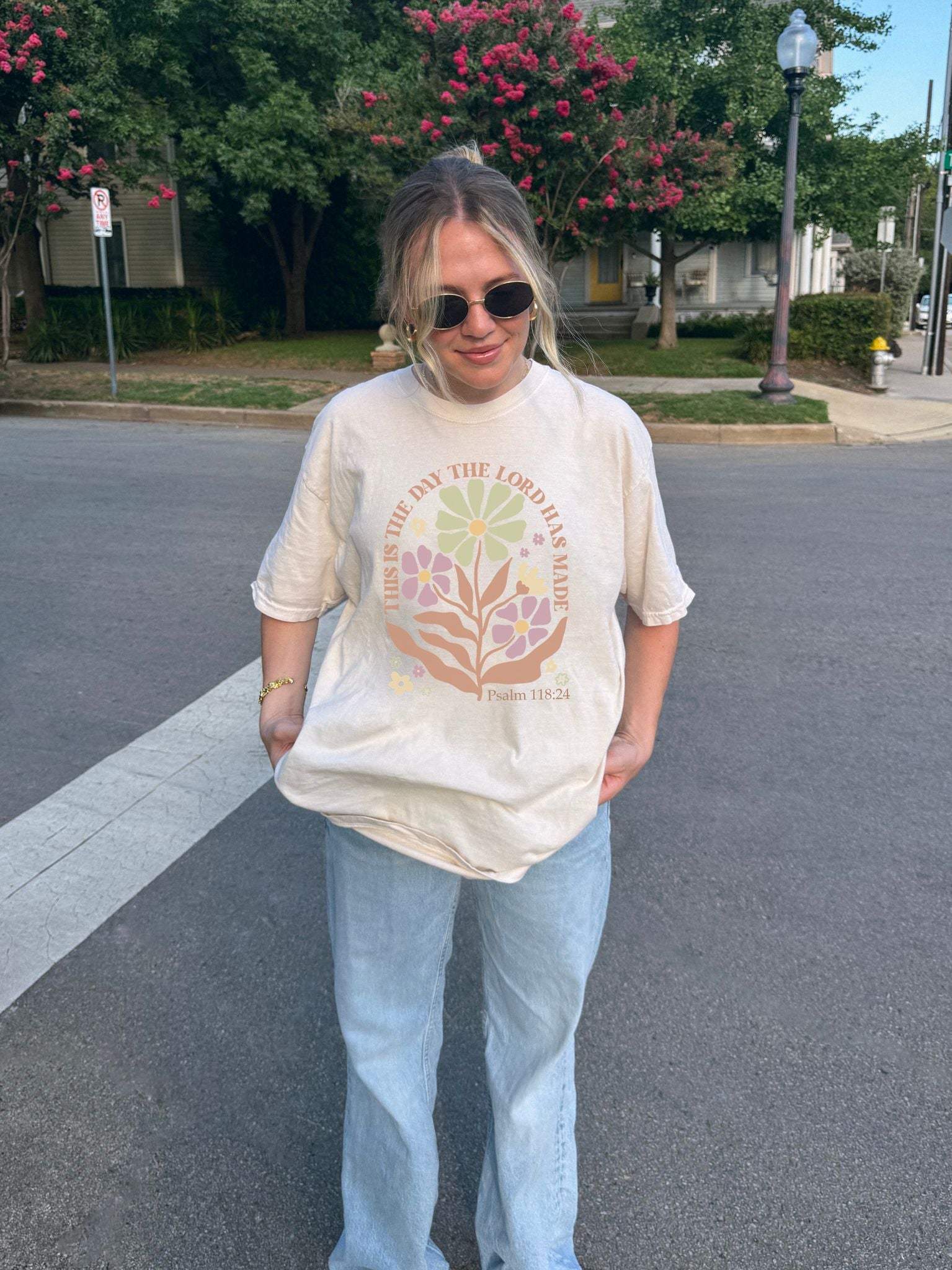T-shirt with 'This is the Day' text, Psalm 118:24 verse, and floral design with protective hands in sage green, pink, and terracotta colors