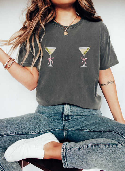 T-shirt design with two martini glasses containing olives and pink bow details creating a humorous cocktail theme