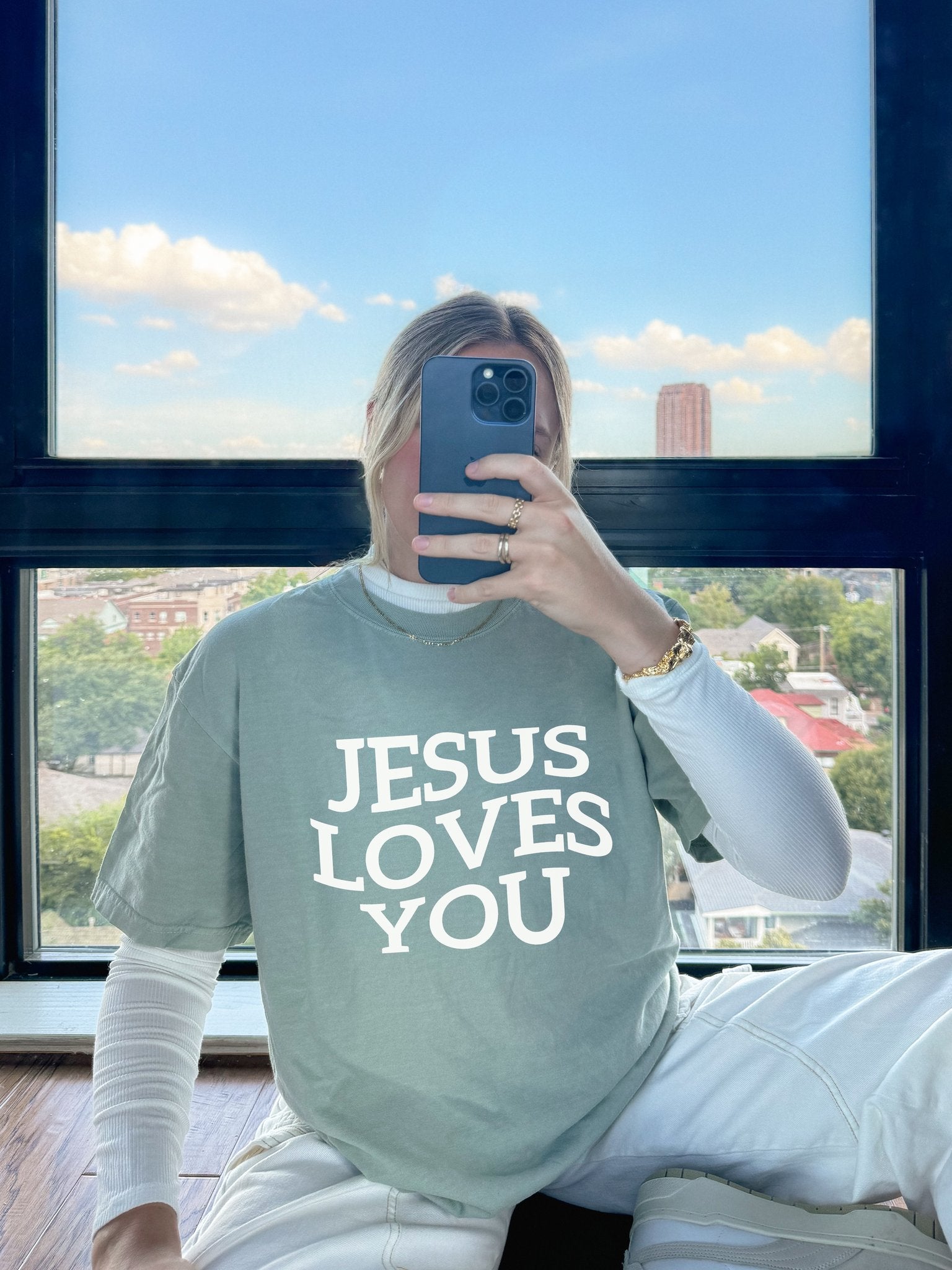 T-shirt with bold black text reading 'JESUS LOVES YOU' in large serif typography