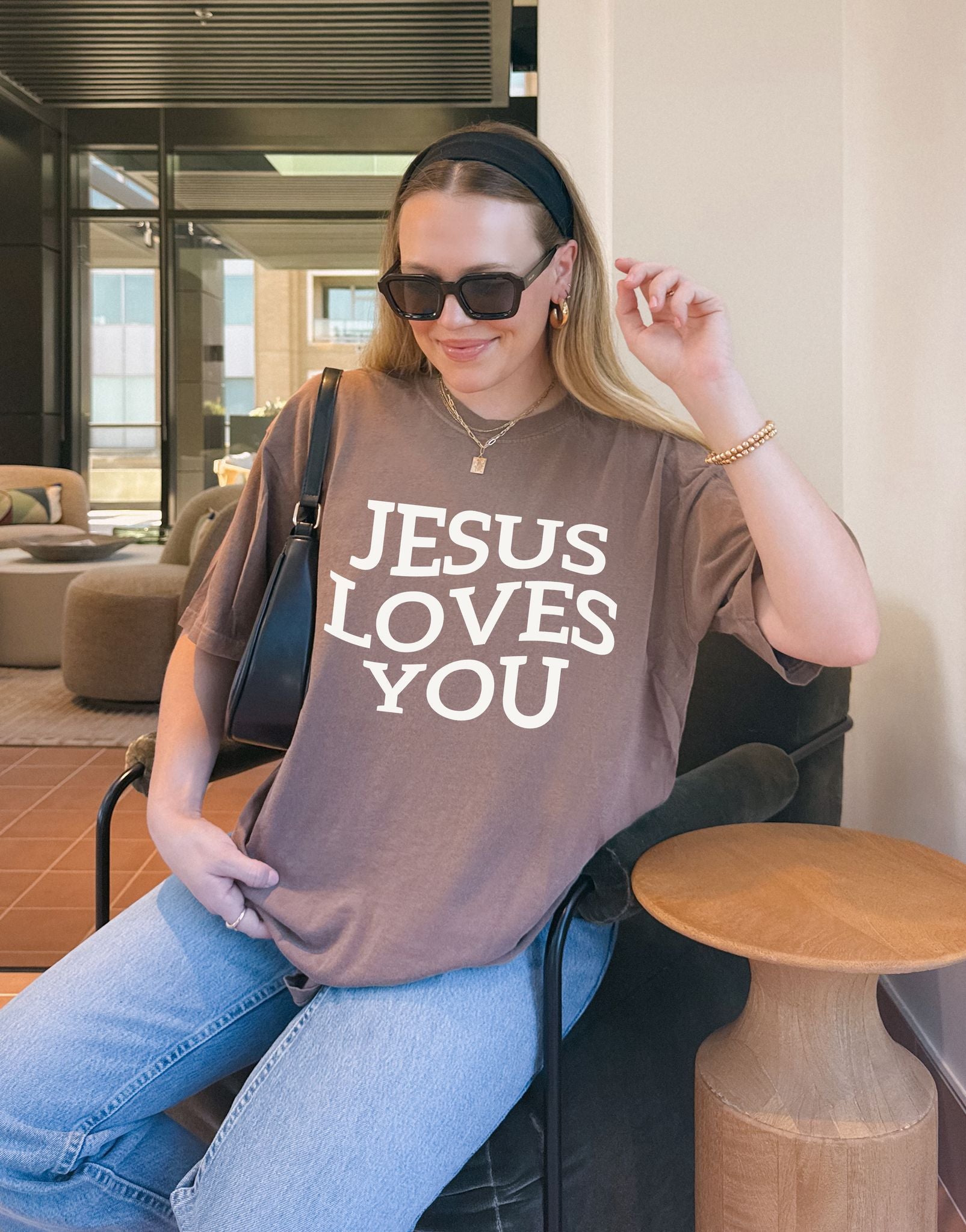 T-shirt with bold black text reading 'JESUS LOVES YOU' in large serif typography