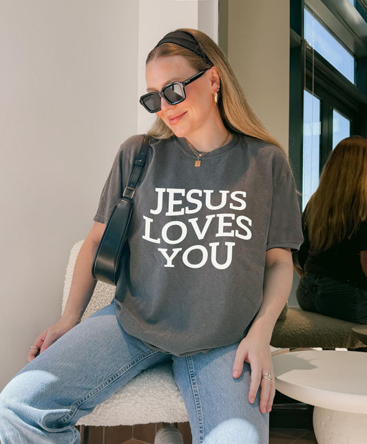 T-shirt with bold black text reading 'JESUS LOVES YOU' in large serif typography