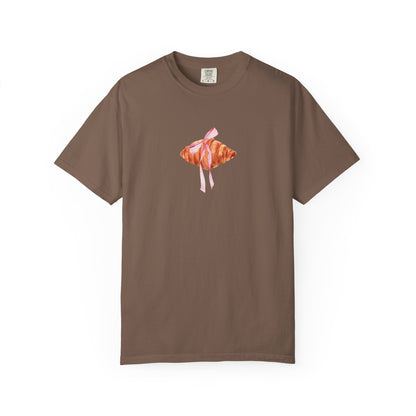 T-shirt with watercolor croissant design featuring golden brown pastry with pink ribbon bow