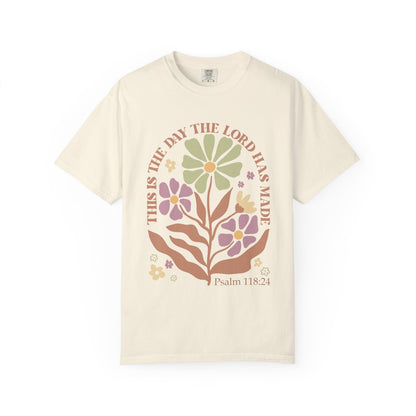 T-shirt with 'This is the Day' text, Psalm 118:24 verse, and floral design with protective hands in sage green, pink, and terracotta colors