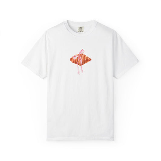 T-shirt with watercolor croissant design featuring golden brown pastry with pink ribbon bow