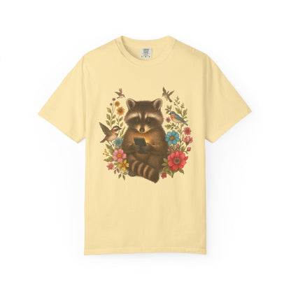 T-shirt design showing raccoon holding phone surrounded by colorful wildflowers and birds