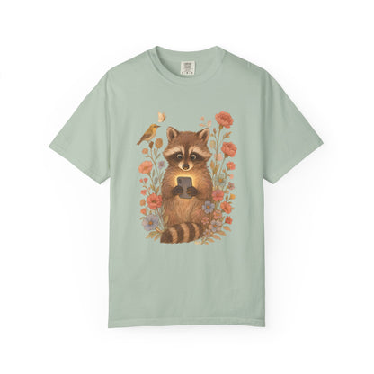 T-shirt with cute raccoon holding smartphone surrounded by coral and blue wildflowers